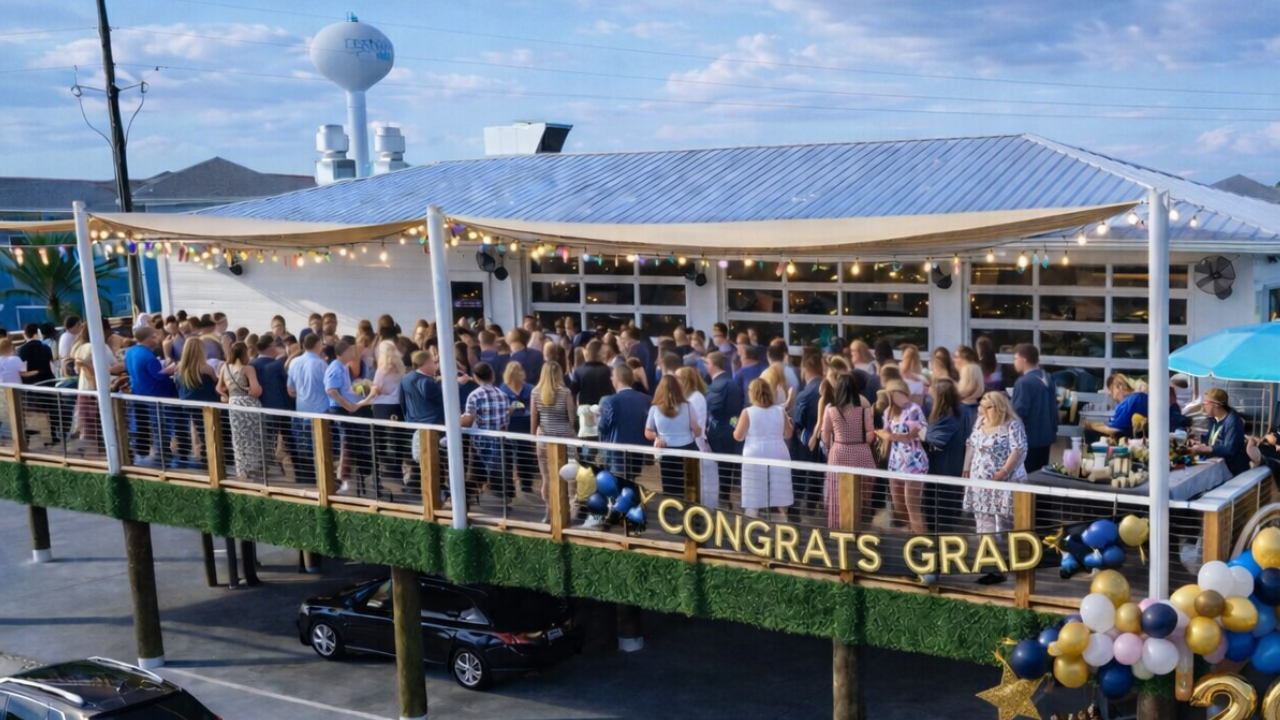 A crowd celebrates graduation on a festive patio at an event space in Fort Walton Beach.